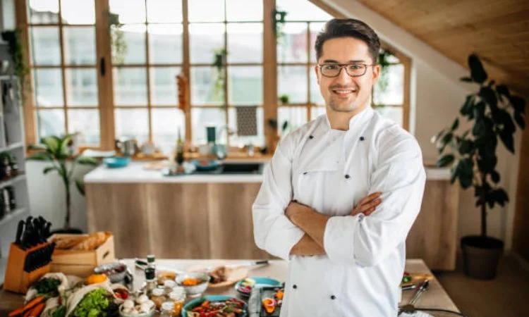 Young man in Chef’s whites posing in his kitchen